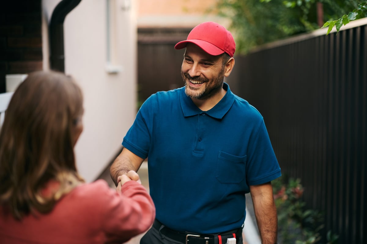 Técnico estrechando la mano de un cliente en su patio